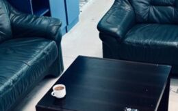 2 schwarze Sofas rund um einen schwarzen Beistelltisch, auf dem eine Tasse Kaffee steht.