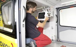 Ein junger Techniker montiert in einem Hubschrauber einen Monitor auf die selbsttragende Innenraumverkleidung Kokon.