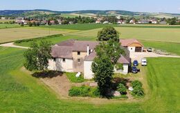 Gebäude der Mühle in Breitenwaida bei Hollabrunn, die Urlaubs-, Therapie- und Beratungszentrum sind, eingebettet in grüner, hügeliger Landschaft.