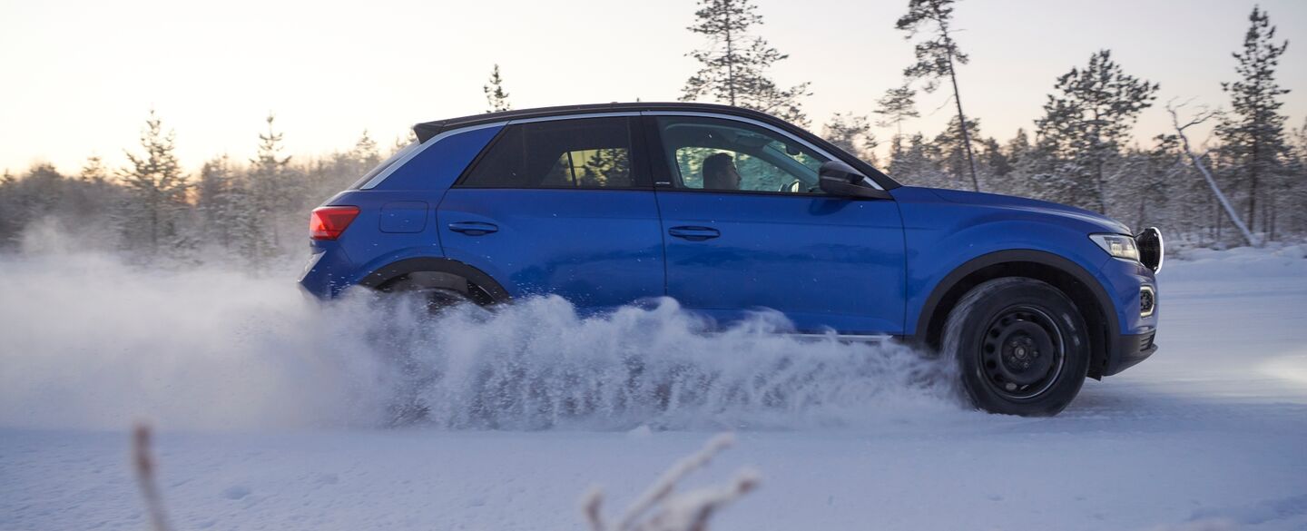 Seitenansicht eines blauen Autos auf einer winterlichen Teststrecke.