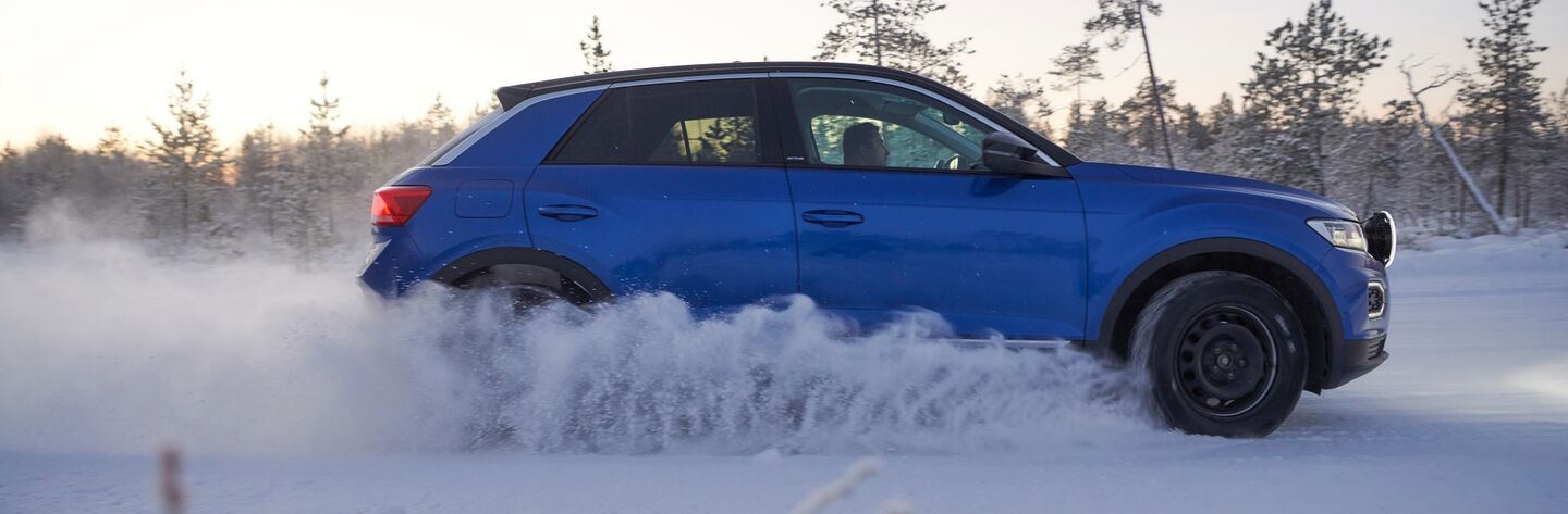 Seitenansicht eines blauen Autos auf einer winterlichen Teststrecke.