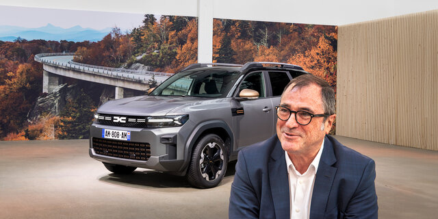 Dacia-CEO Denis Le Vot. Im Hintergrund steht ein graues SUV in einem Studio.