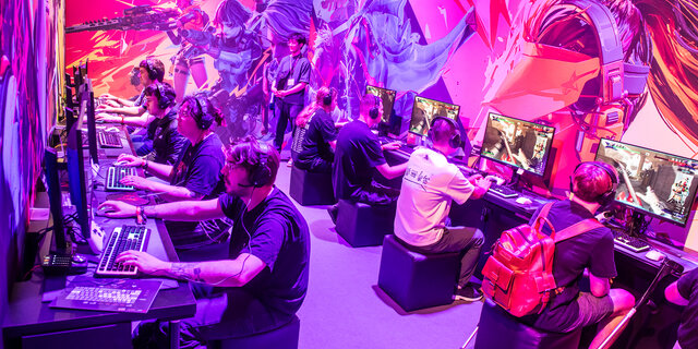  Menschen sitzen vor PC's und spielen Videospiele auf der Gaming-Messe gamescom in Köln.