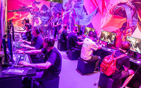  Menschen sitzen vor PC's und spielen Videospiele auf der Gaming-Messe gamescom in Köln.