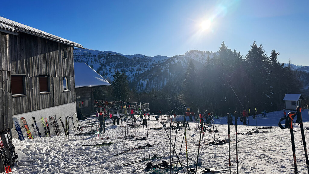 Blick auf die Sonnalm am Jagerspitz am Kasberg. Im Vordergrund Ski und Skistöcke im Schnee.