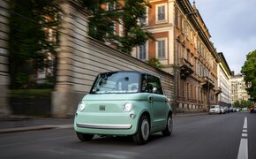 Ein lindgrünes kleines Auto fährt durch die Stadt